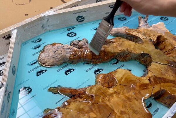 brushing a blue coral leaf made with deep pour epoxy resin and olivewood