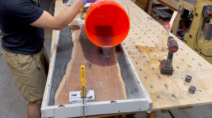 Pouring epoxy resin to walnut for making epoxy resin table